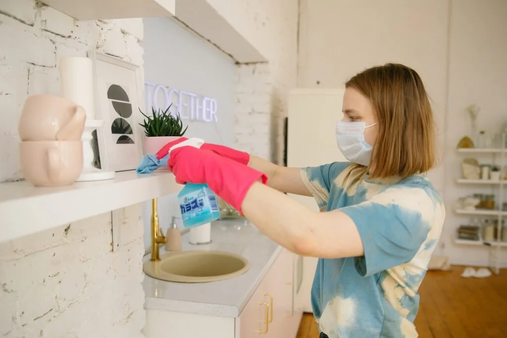 woman wearing face mask while cleaning the kitchen