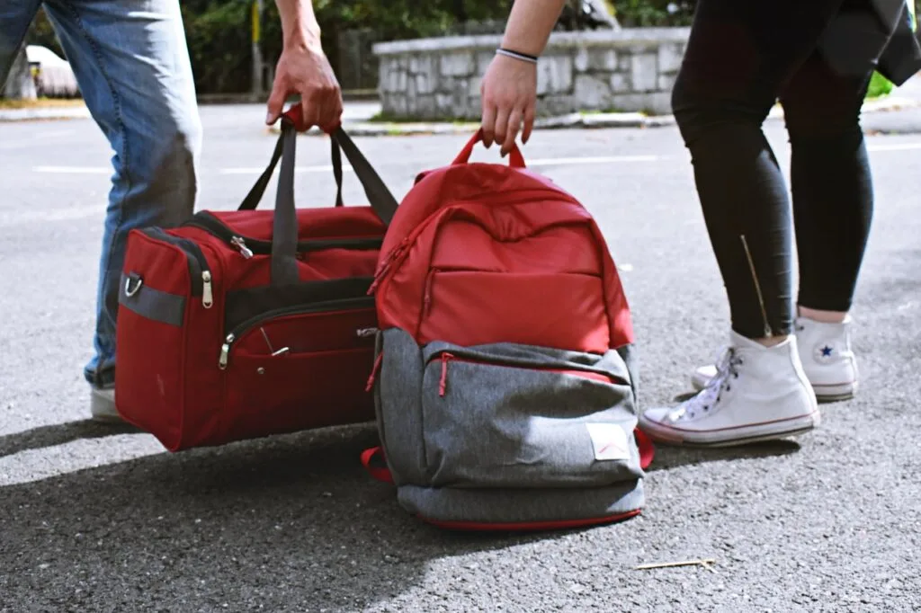 two person carrying red backpack