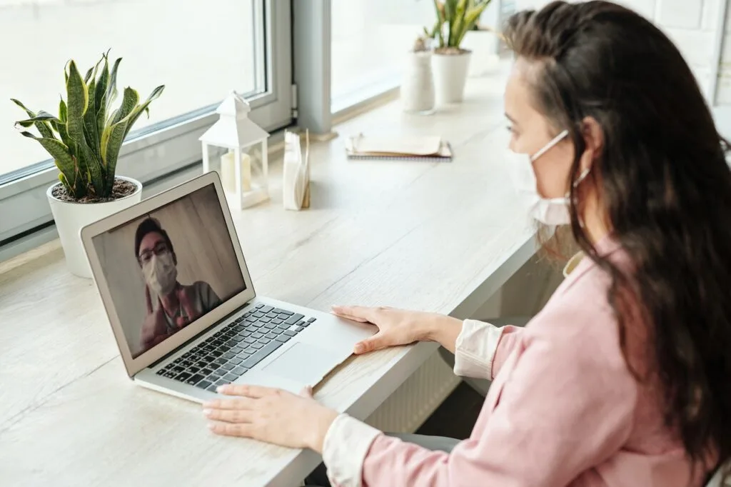 woman wearing mask front laptop