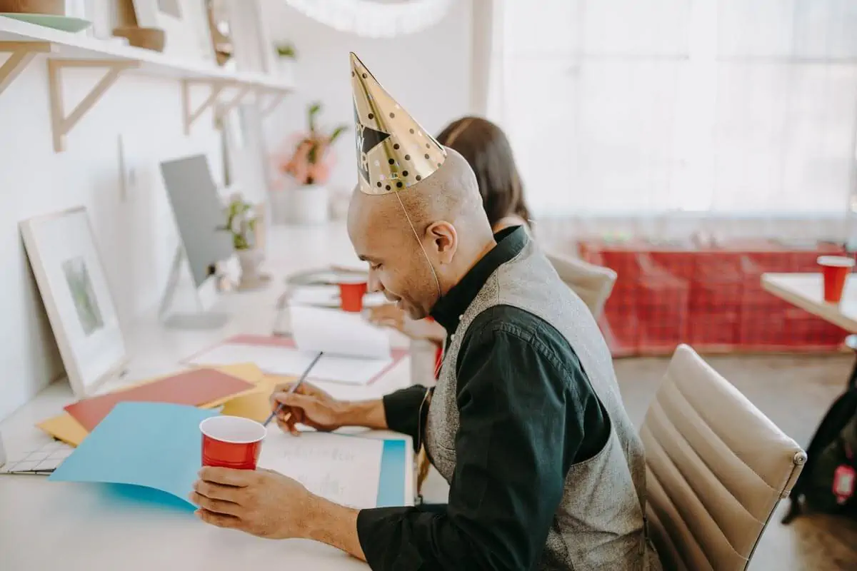 a side view of a man wearing party hat while holding a red cup