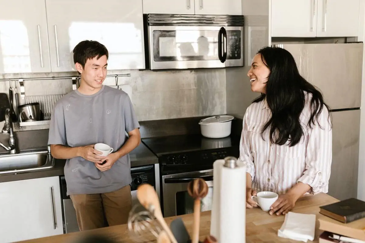 a young couple holding cups of coffee in a kitchen