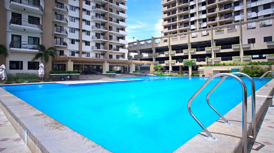 Daytime view of a swimming pool next to a luxurious-looking condo unit
