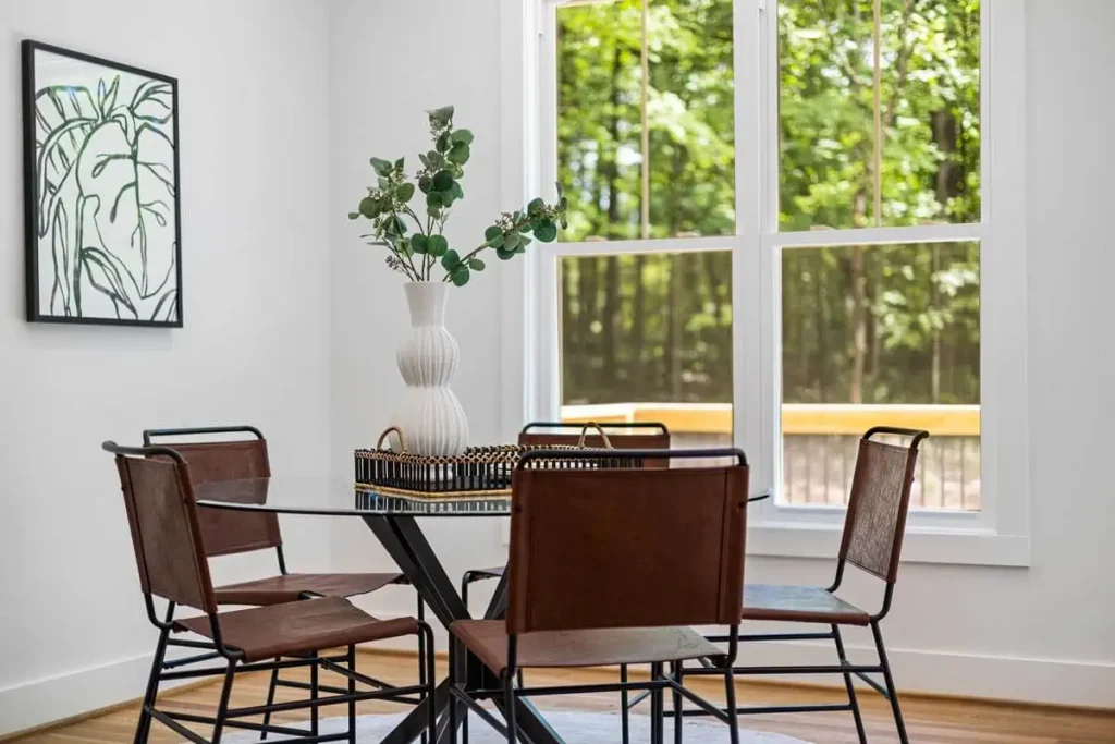 table with plant and chairs near windows