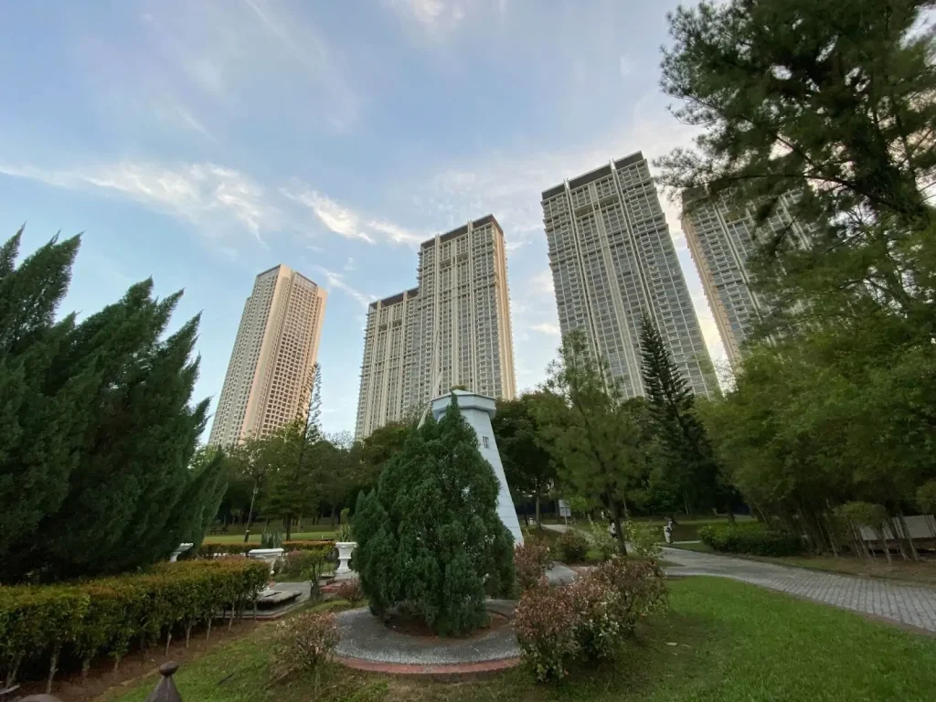 a statue in a park with tall buildings in the background