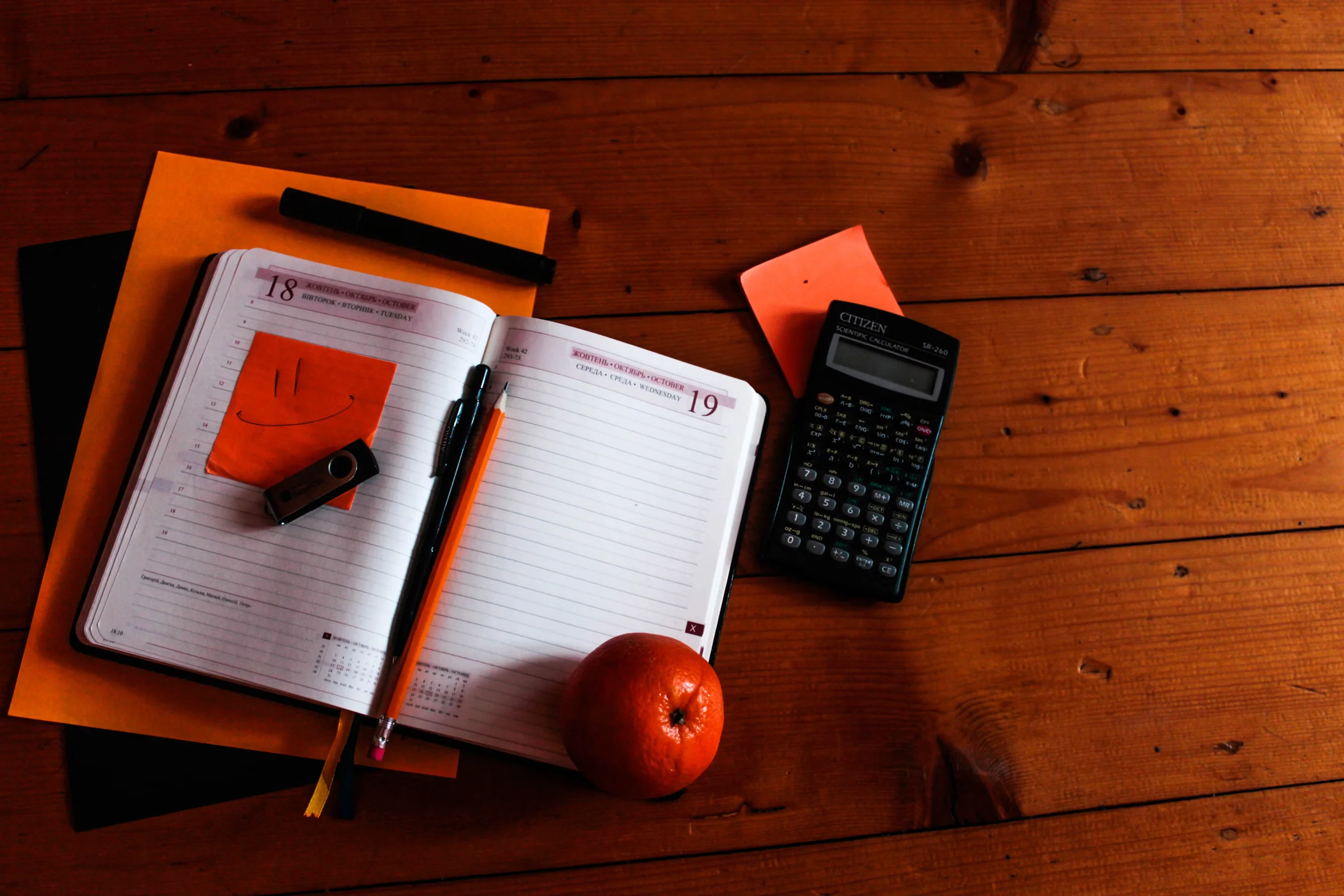 black scientific calculator orange and notebook on table