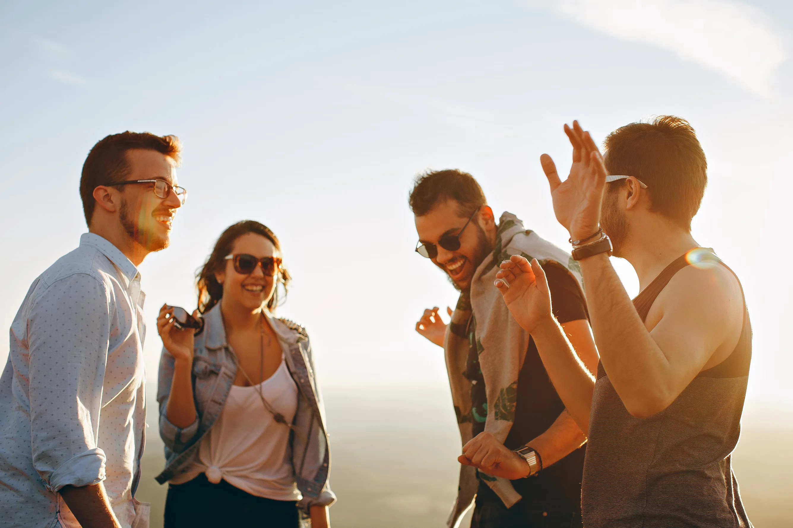 three men and a woman laughing during daytime