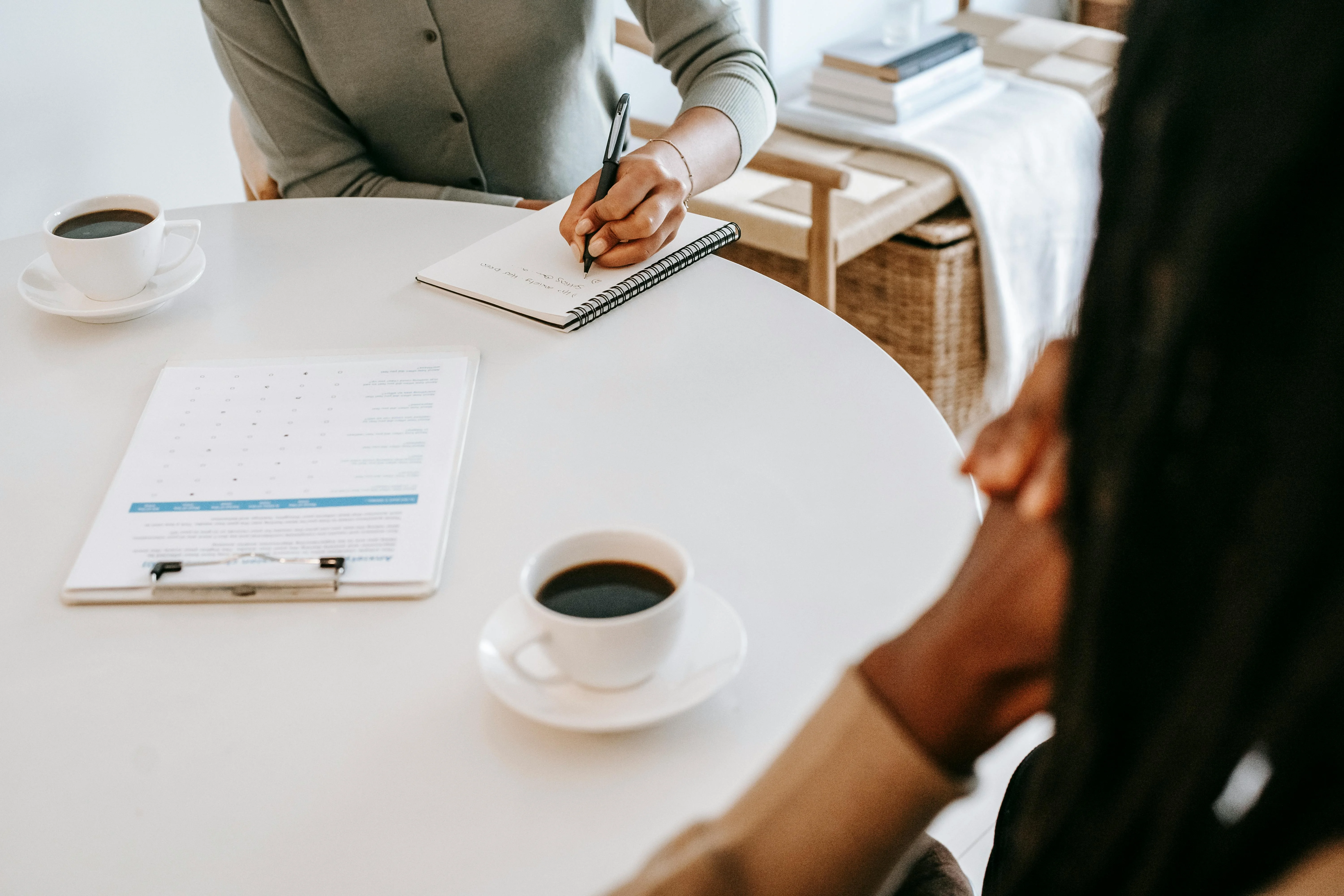 interviewer writing in notepad and talking to job seeker