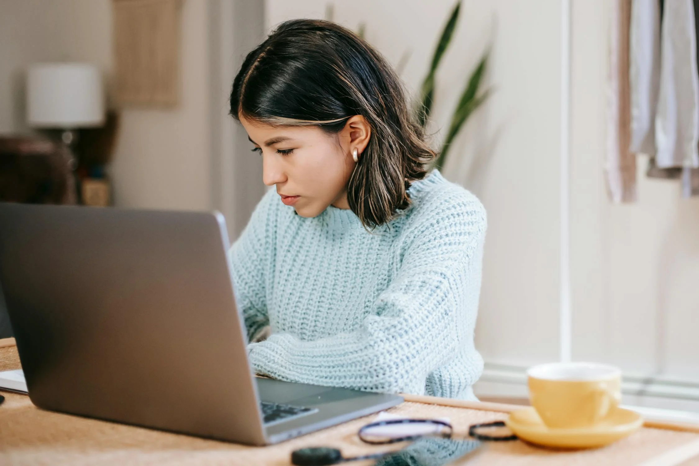 female using laptop near coffee cup