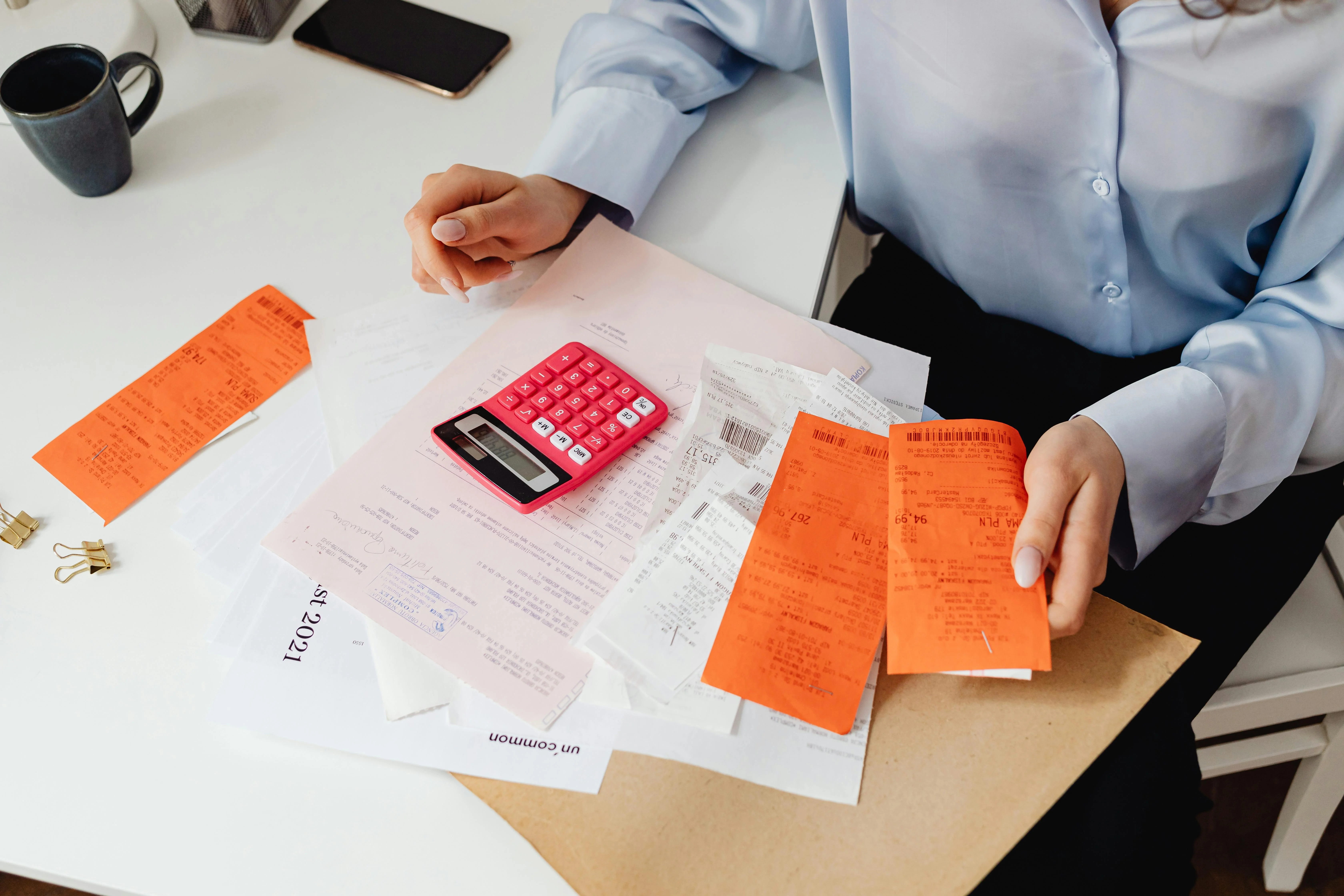 person holding receipts and using calculator