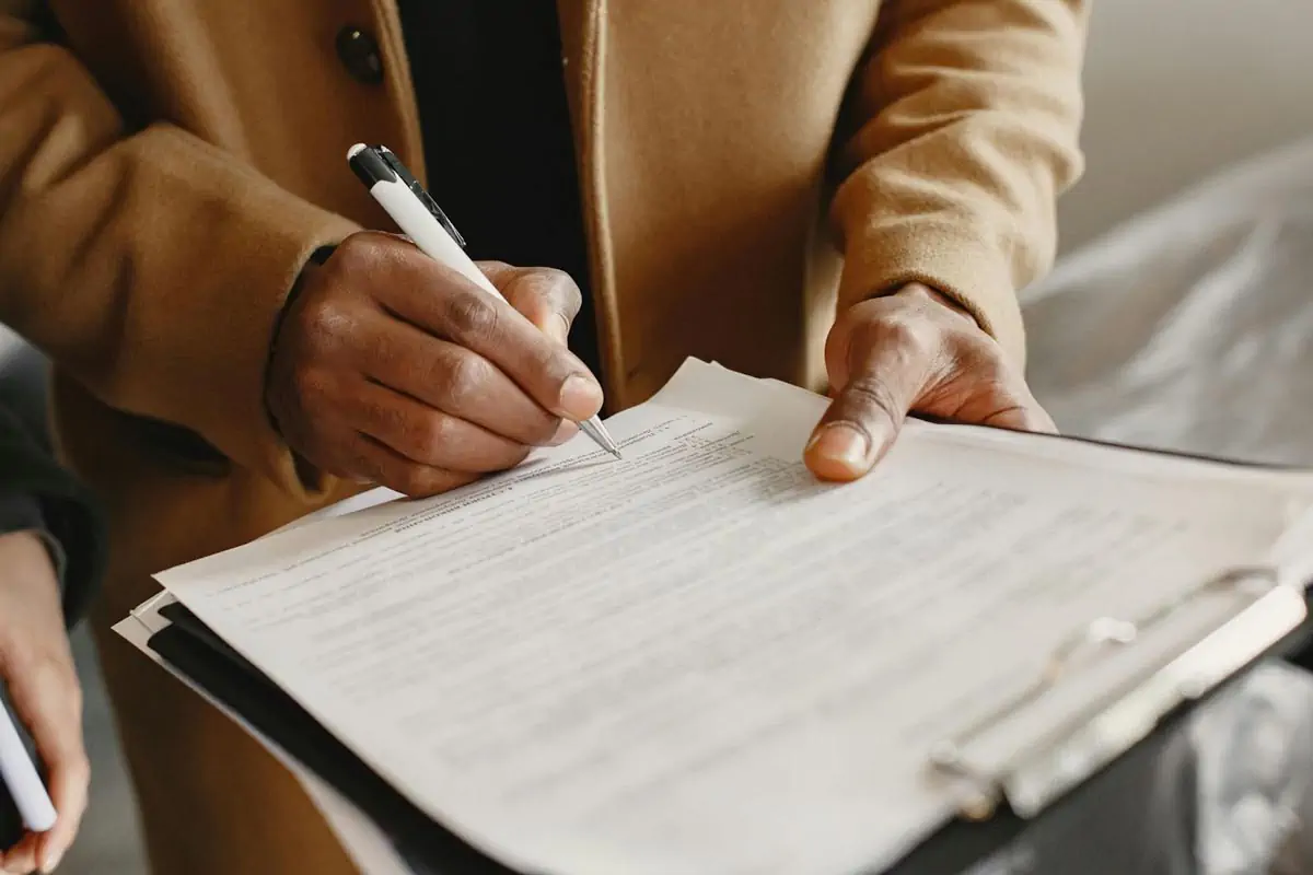 a person writing on white paper while holding a pen