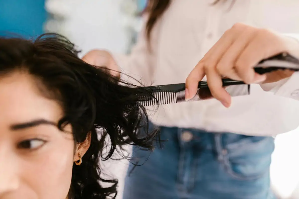 a woman in blue denim jeans holding a hair comb