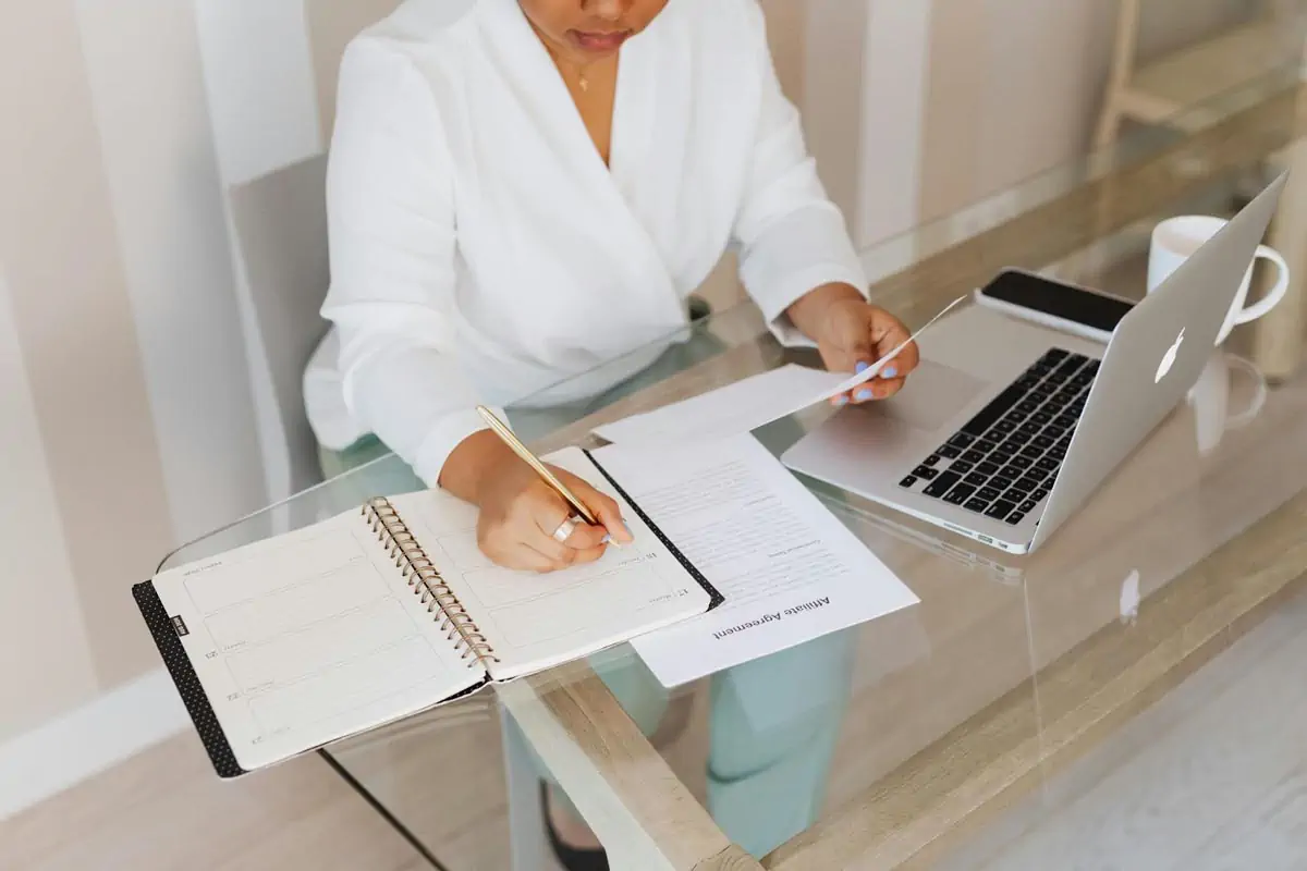 person in white top writing on notebook