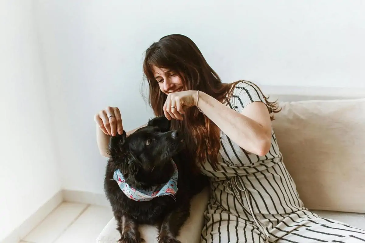 woman sitting by black dog on sofa