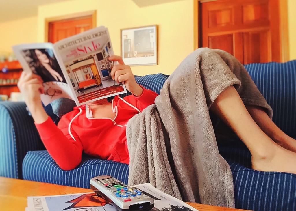 girl reading magazine lying couch